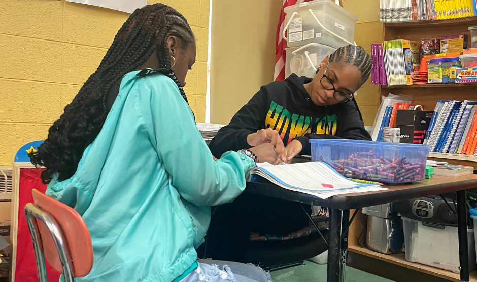 HUASB student helping younger student with assignment. 